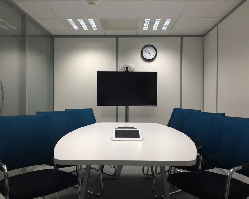 Conference room with a wall-mounted display, video conferencing camera and table controller